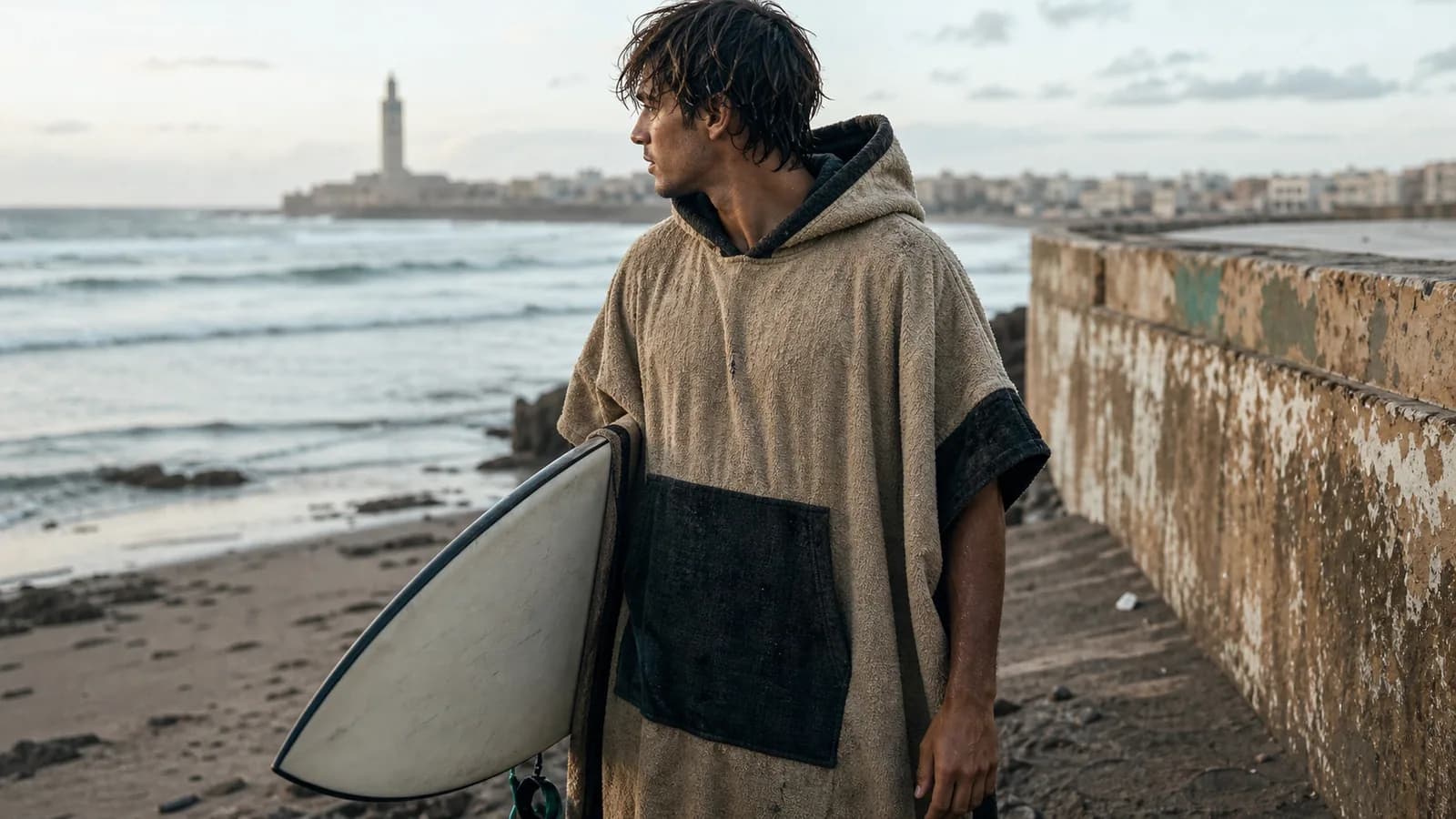 Surfer wearing a textured changing poncho beside the Casablanca coast after a session
